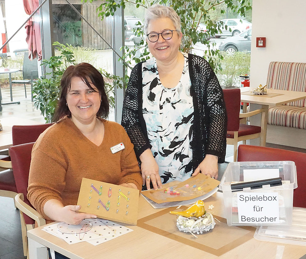 Zwei Frauen präsentieren Aktivierungsbretter und Spielebox für Besucher